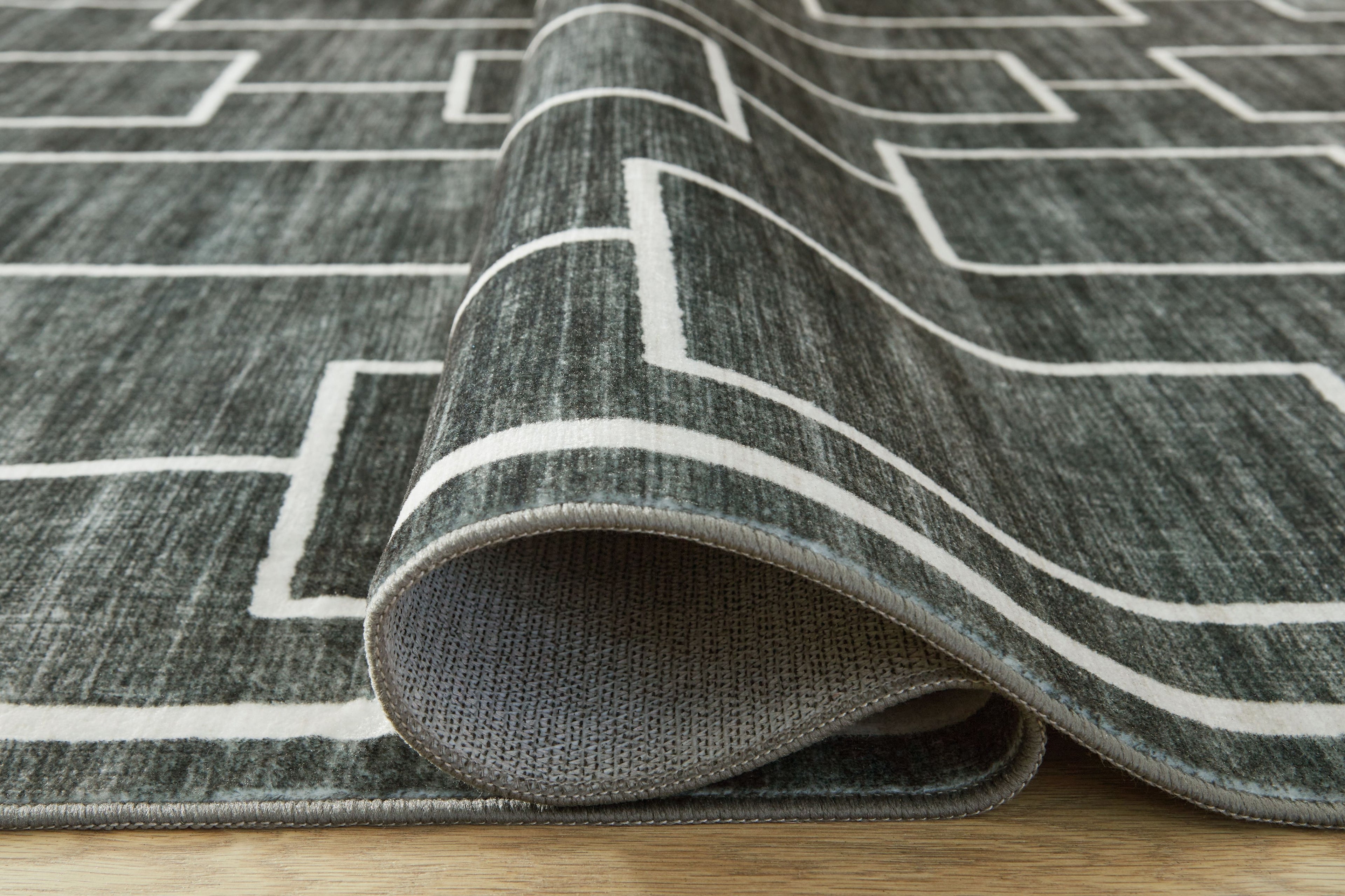 Elderland washable rug edge folded back, showing flat texture and white pattern lines