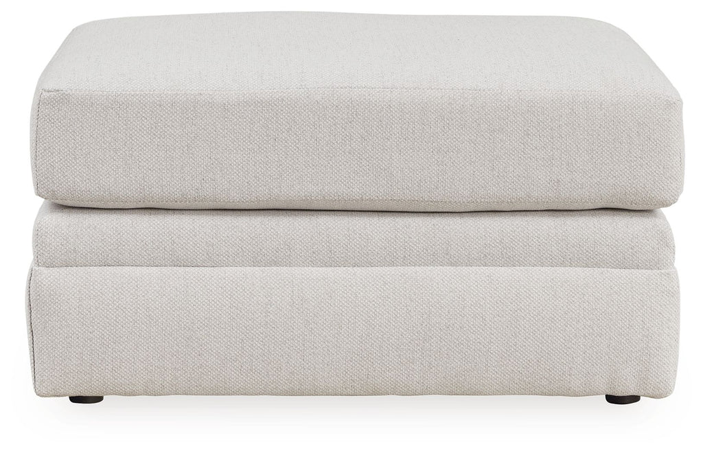 Light beige ottoman with layered rectangular sides, flat top cushion, short feet