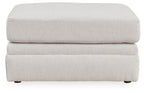 Light beige ottoman with layered rectangular sides, flat top cushion, short feet