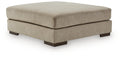 Oversized accent ottoman in dune beige fabric, rounded top and dark wood legs.