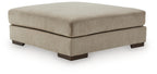 Oversized accent ottoman in dune beige fabric, rounded top and dark wood legs.