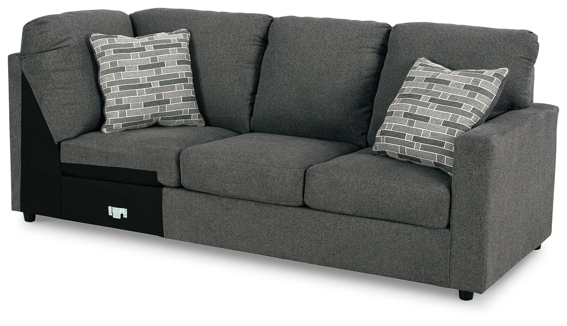 Dark gray wedge sofa with three seat cushions, two patterned pillows, and corner backrest