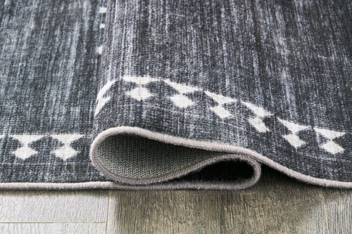Corner of black rug with cream geometric pattern and gray speckled texture