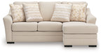 Light beige sofa chaise with three seat cushions and decorative jute-pattern throw pillows.