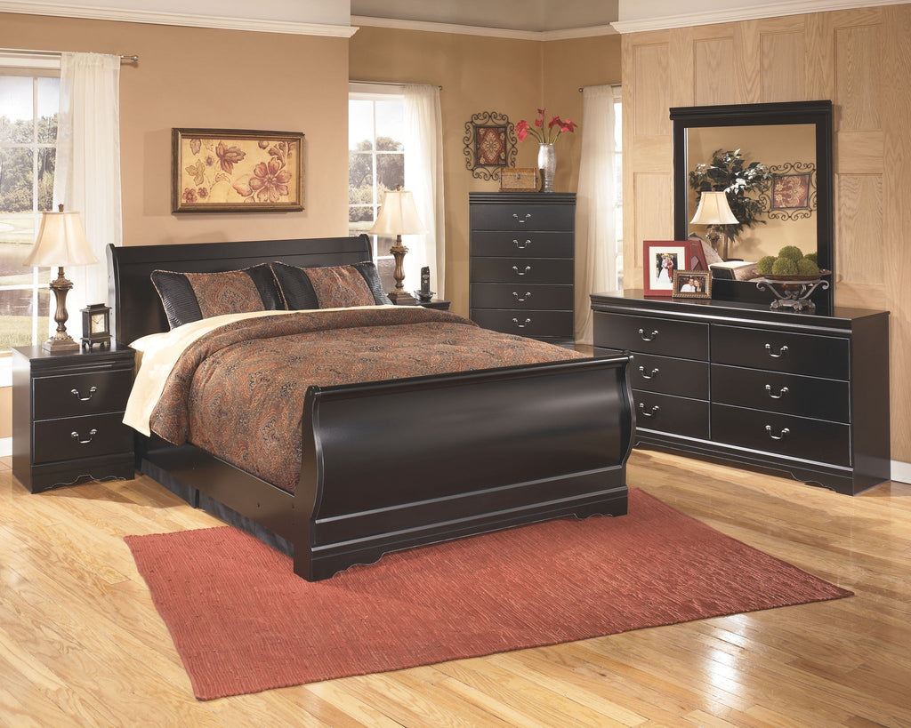 Black dresser with mirror, multiple drawers, and metal pulls, styled with decor.