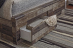 Dark gray panel bed with side drawer and upholstered headboard, shown from the foot