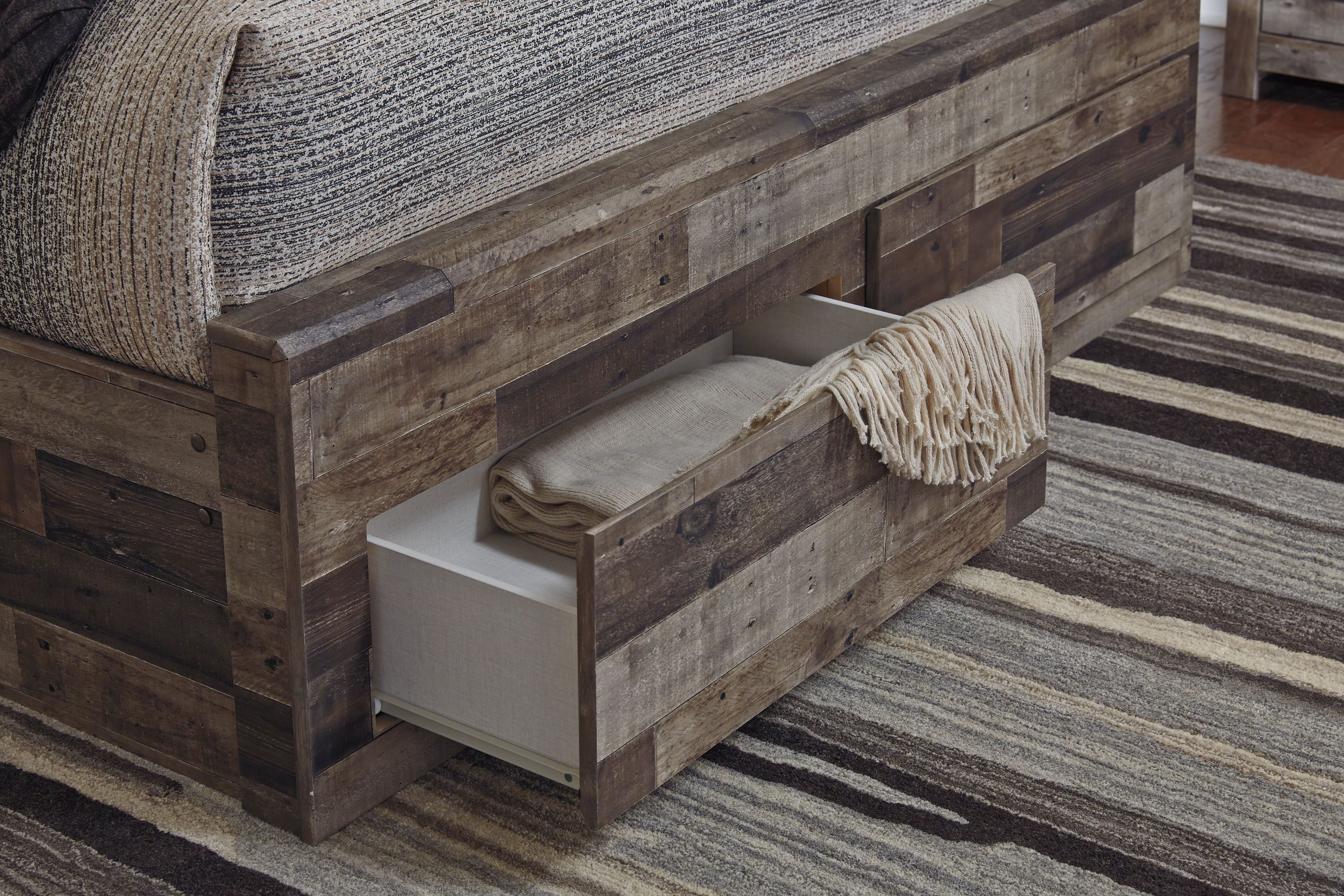 Dark gray panel bed with side drawer and upholstered headboard, shown from the foot