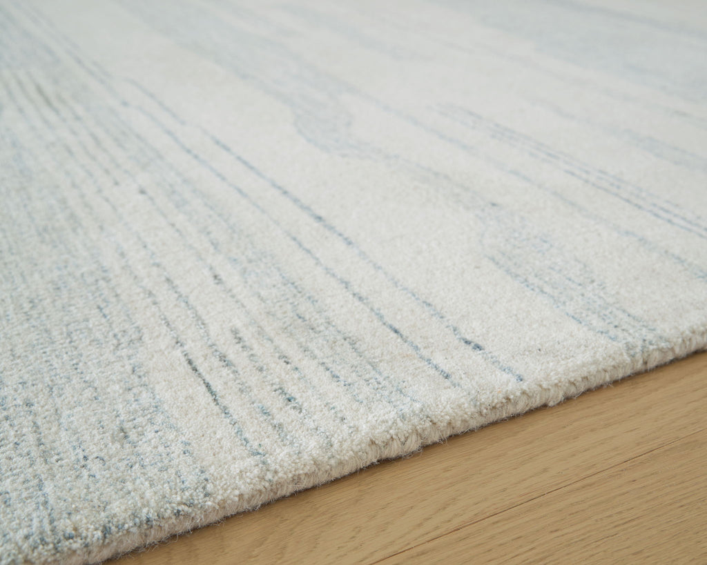 Light blue and white rug corner with distressed lines on a textured surface