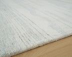 Light blue and white rug corner with distressed lines on a textured surface