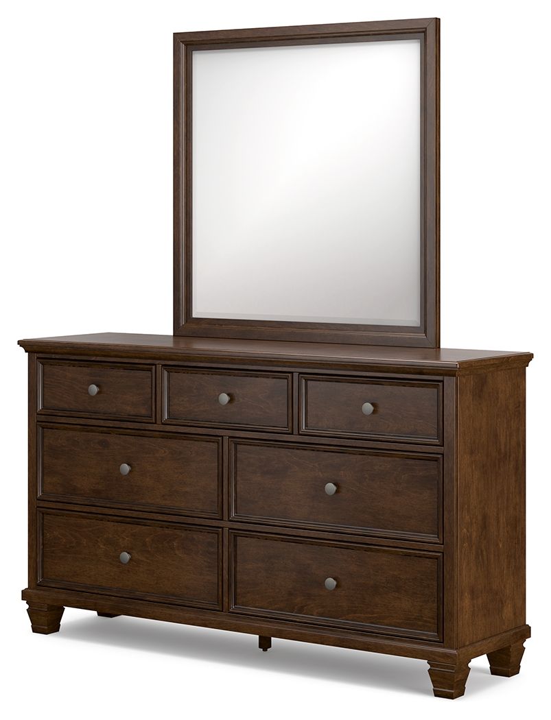 Brown dresser with framed mirror and multiple drawer fronts, round metal knobs.