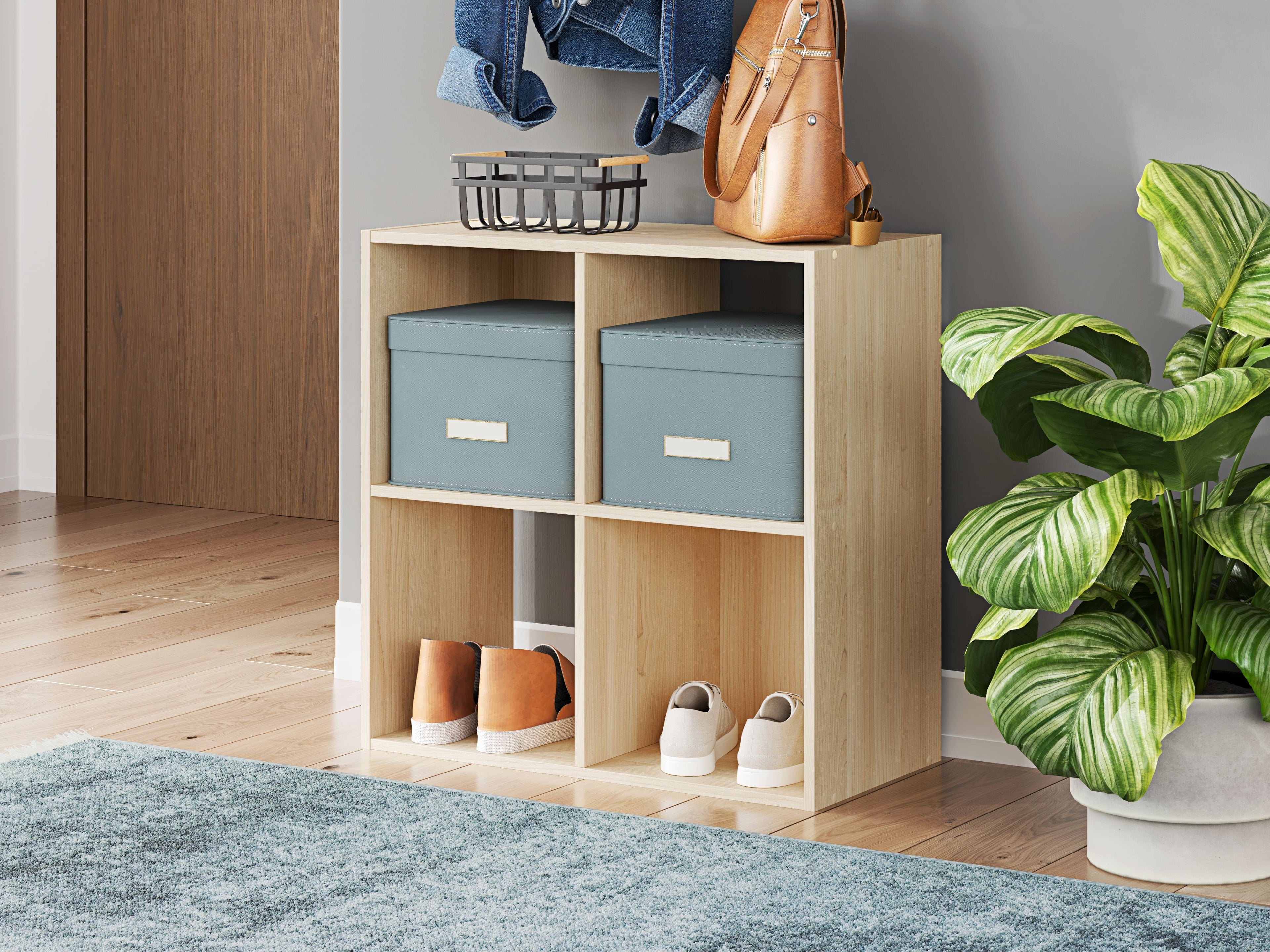 Light wood cube organizer with open compartments holding storage bins and small items