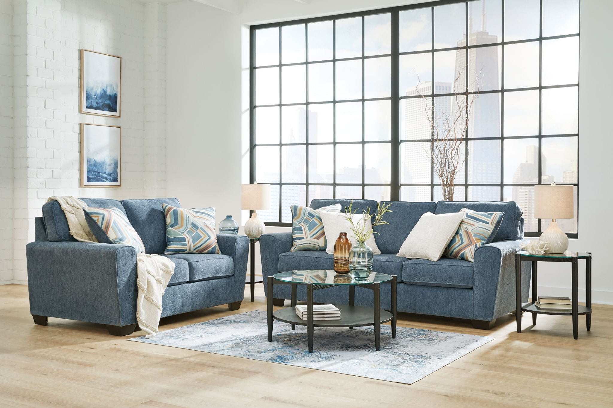 Blue fabric living room set with sofa, chairs, ottoman, and accent pillows