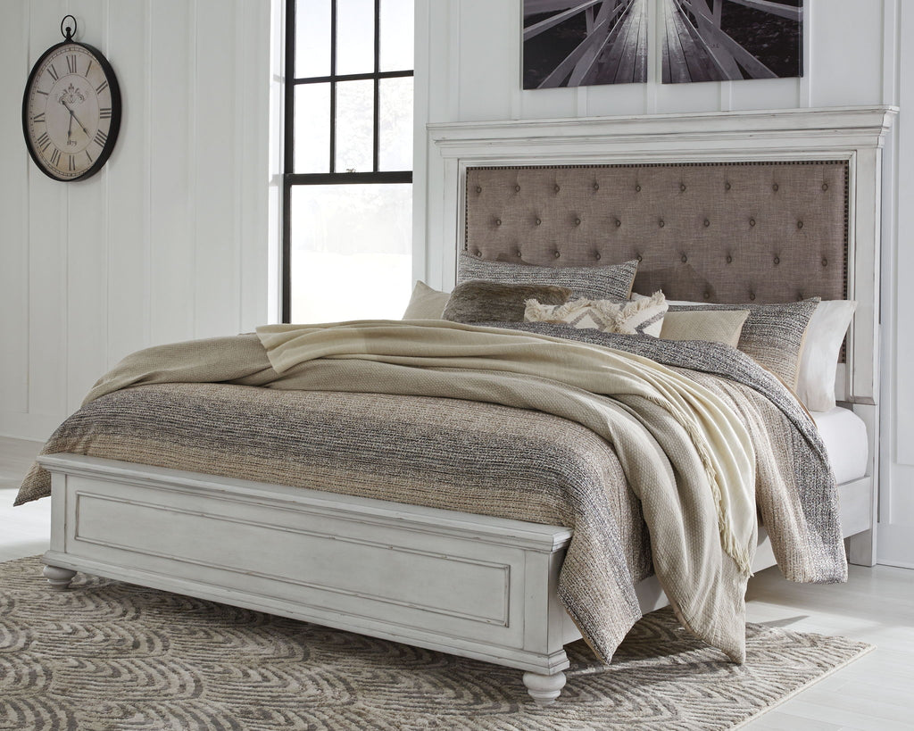Upholstered panel bed in white with tufted taupe headboard and gray bedding