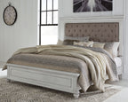 Upholstered panel bed in white with tufted taupe headboard and gray bedding