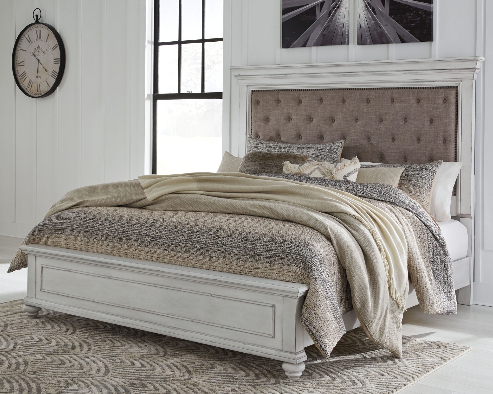 Upholstered panel bed in white with tufted taupe headboard and gray bedding