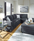 Dark slate sectional sofa with chaise and throw pillows in a living room setup