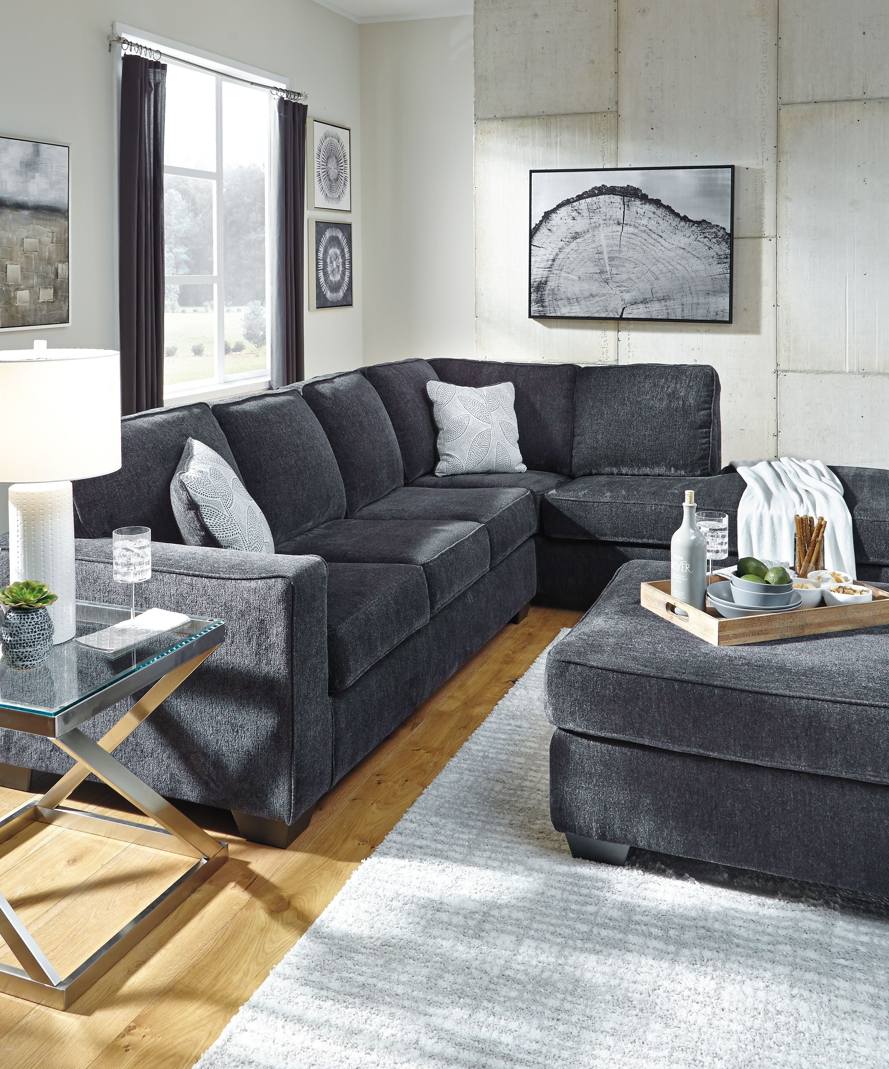 Dark slate sectional sofa with chaise and throw pillows in a living room setup