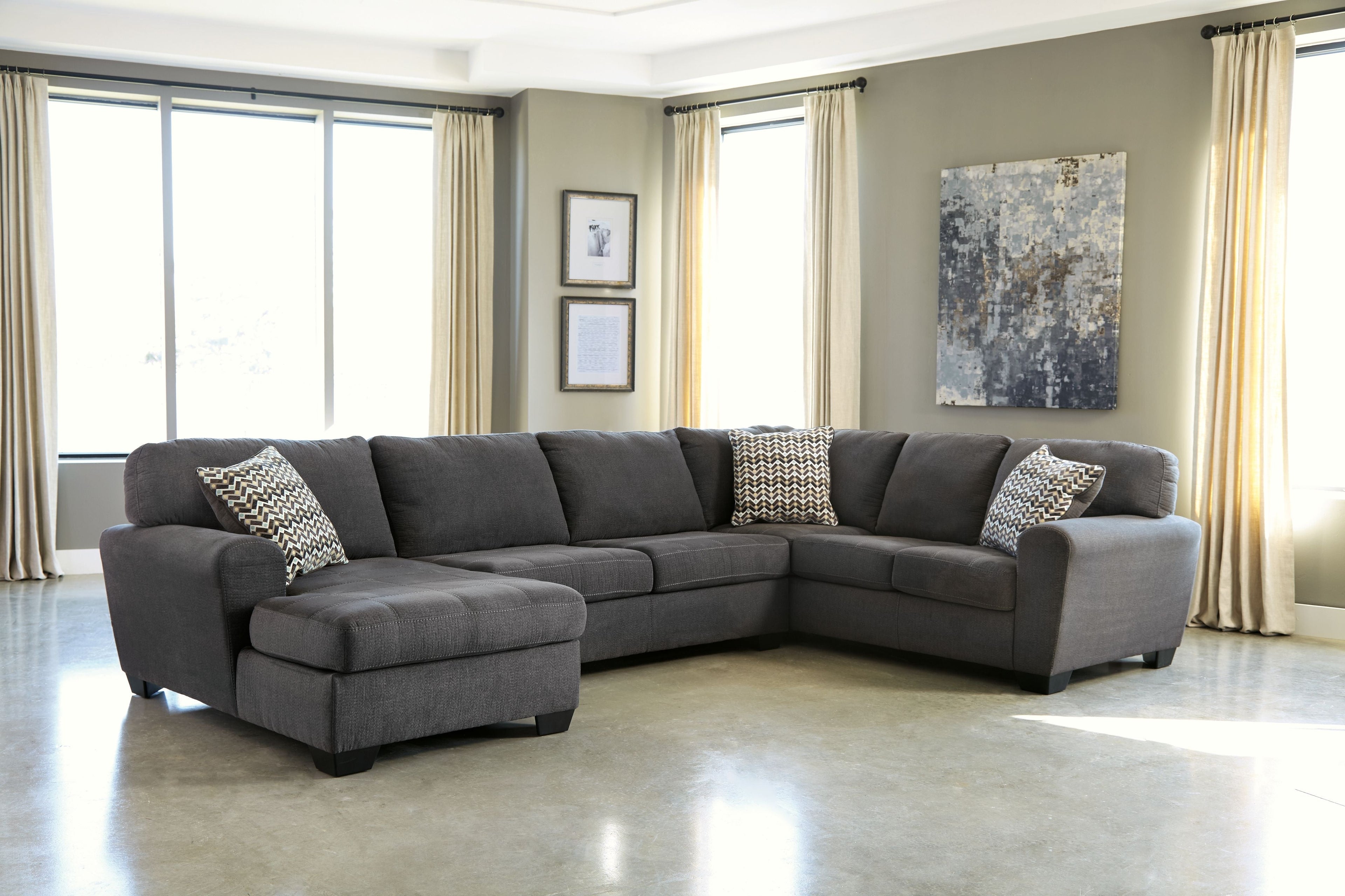 Slate sectional sofa with chaise and two patterned throw pillows on dark gray upholstery