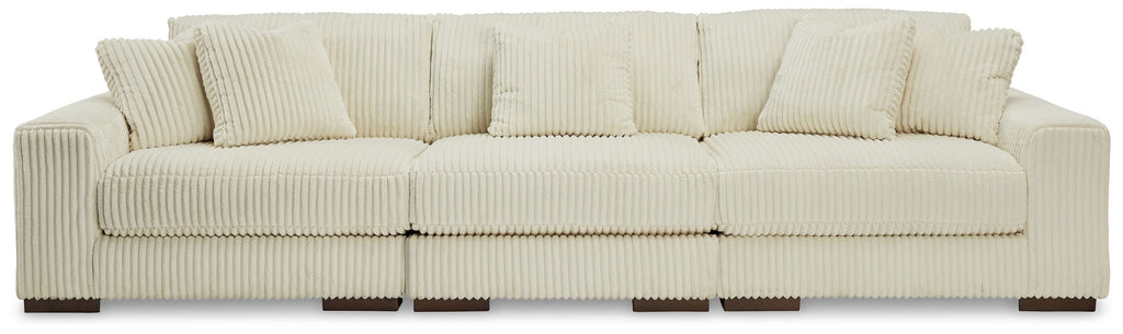 Ivory sectional sofa with three back cushions, track arms, and ribbed upholstery.