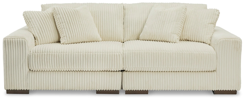 Ivory sectional sofa with plush tufted back cushions and ribbed channel texture.