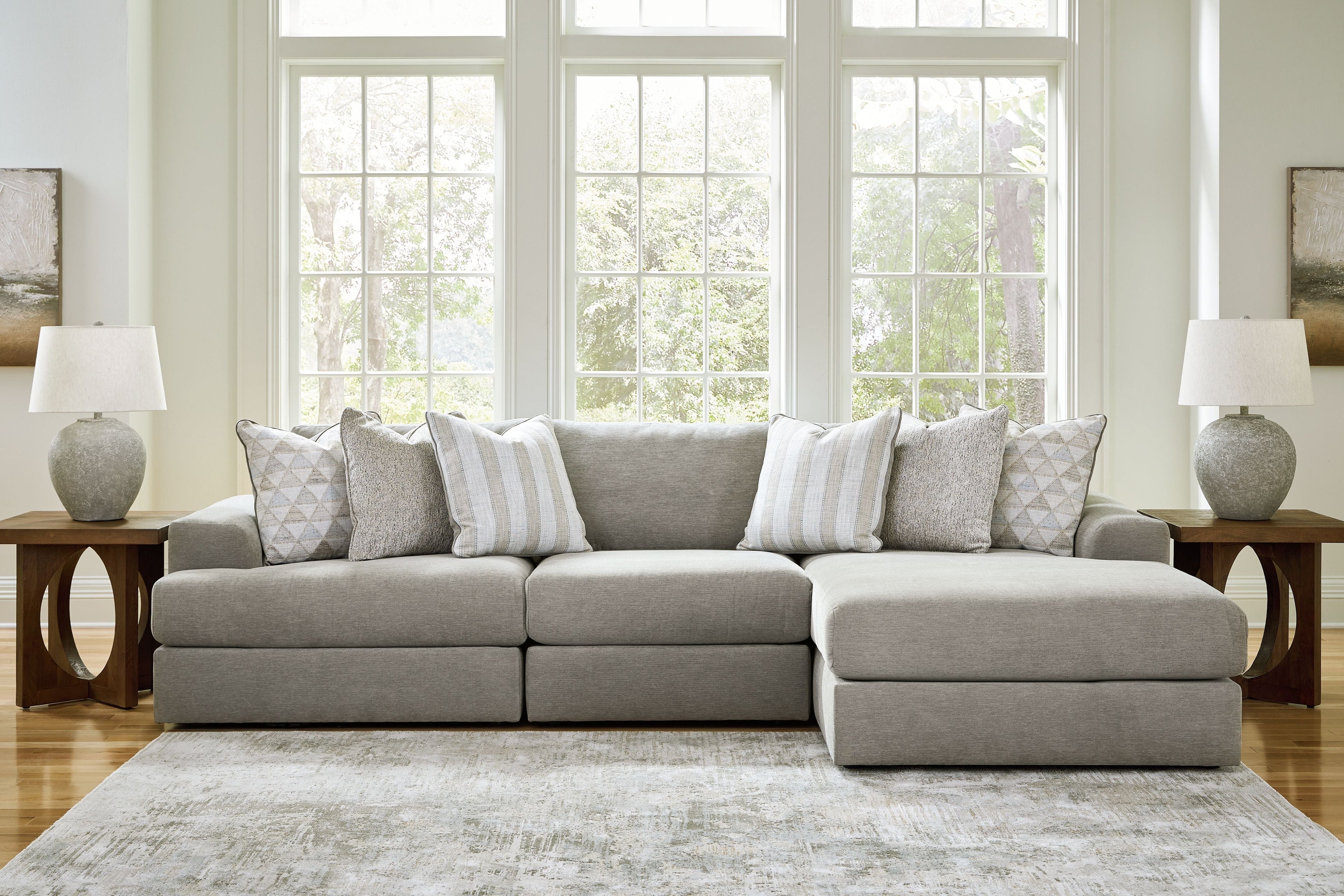 Light gray sectional sofa with ottoman-style chaise and decorative throw pillows.