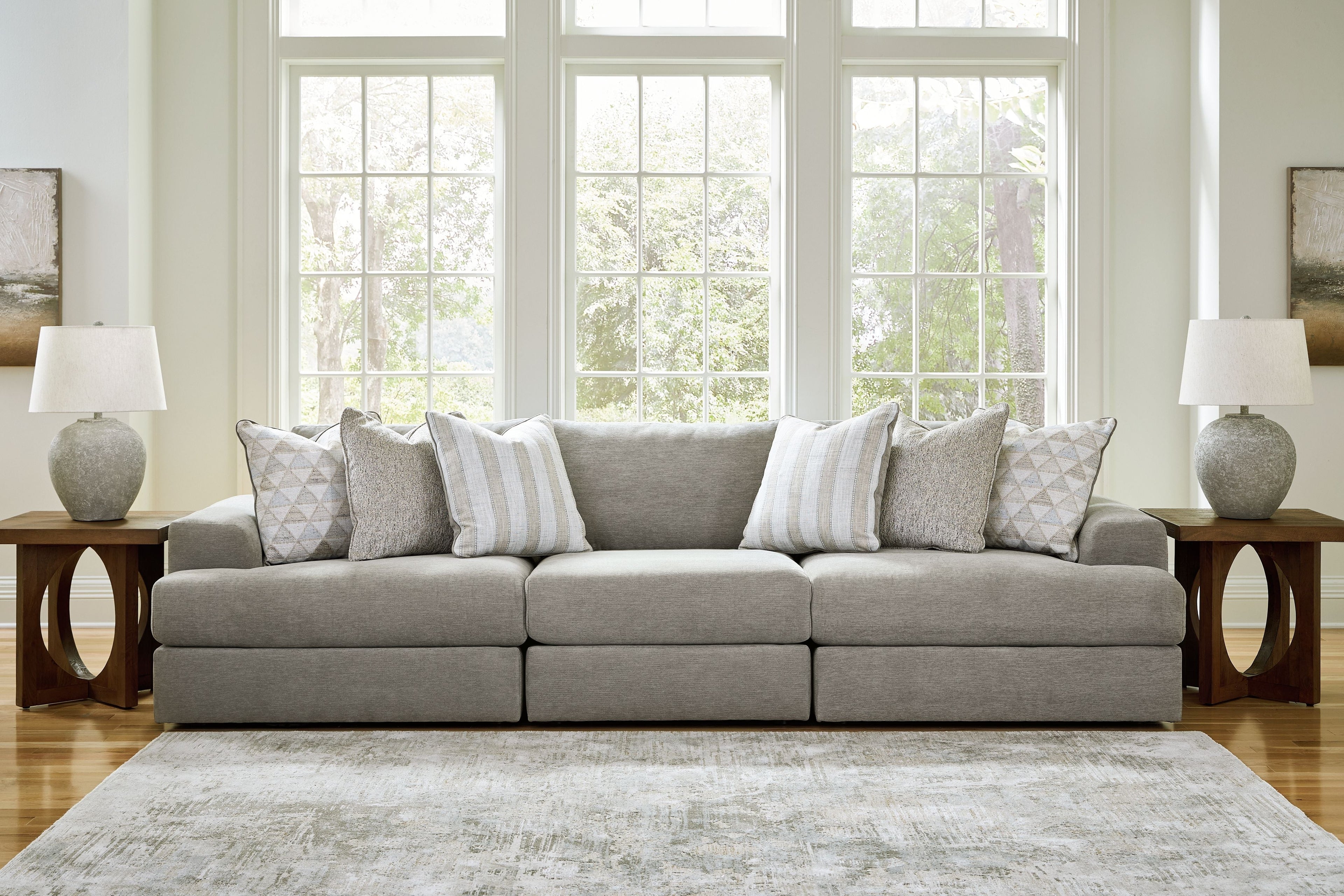 Light gray sectional sofa with chaise section and assorted striped and textured throw pillows.