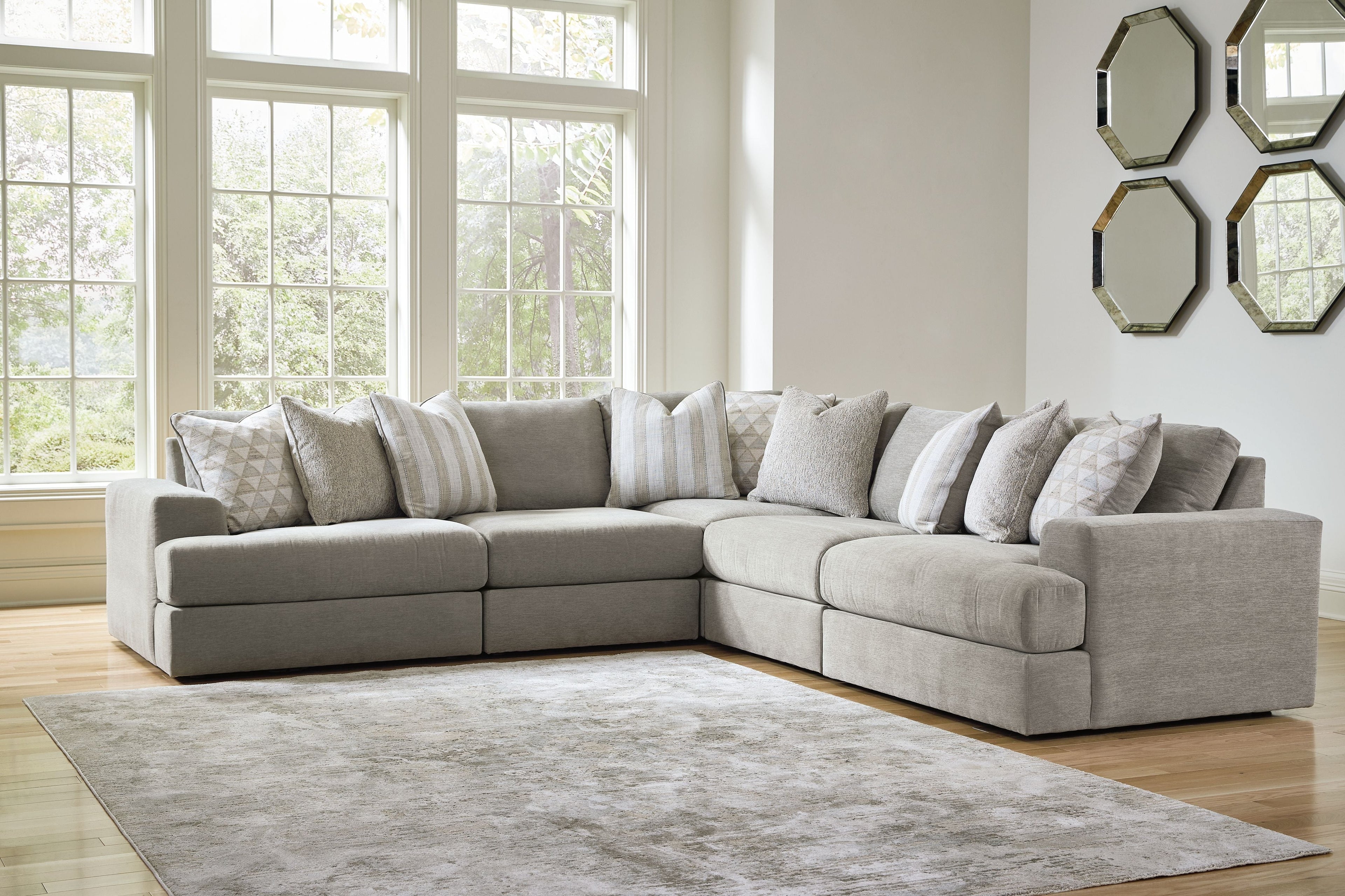 Light gray sectional sofa with chaise arm and multiple throw pillows in neutral tones.