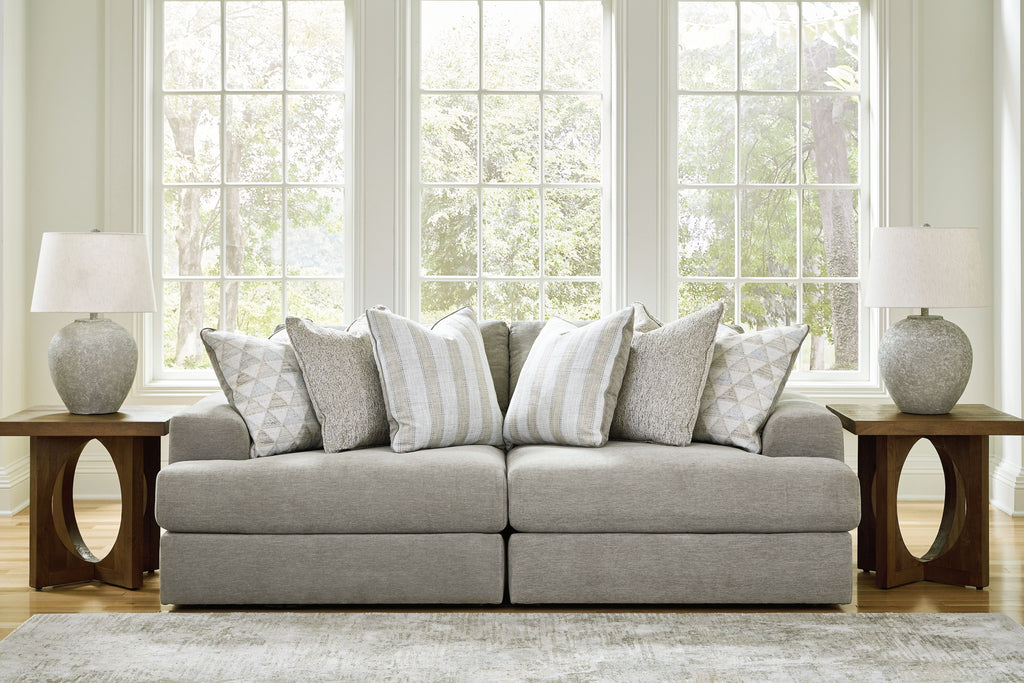 Light gray sectional sofa with two-seat center and multiple patterned throw pillows.