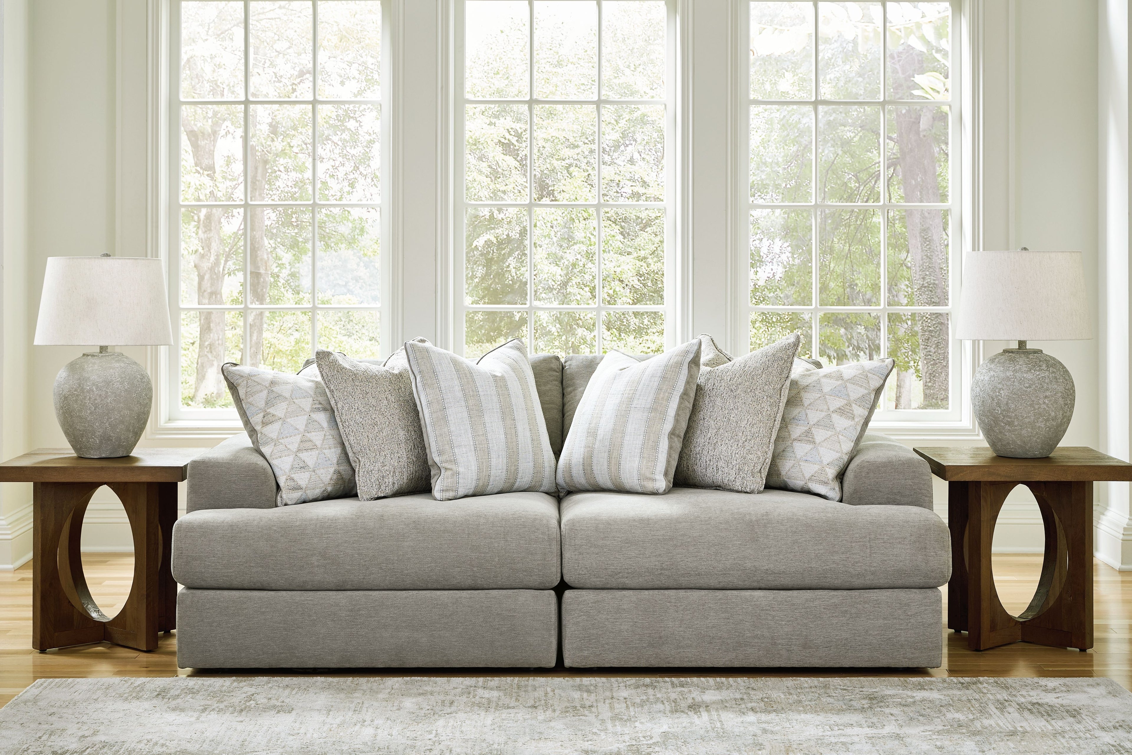 Light gray sectional sofa with two-seat center and multiple patterned throw pillows.
