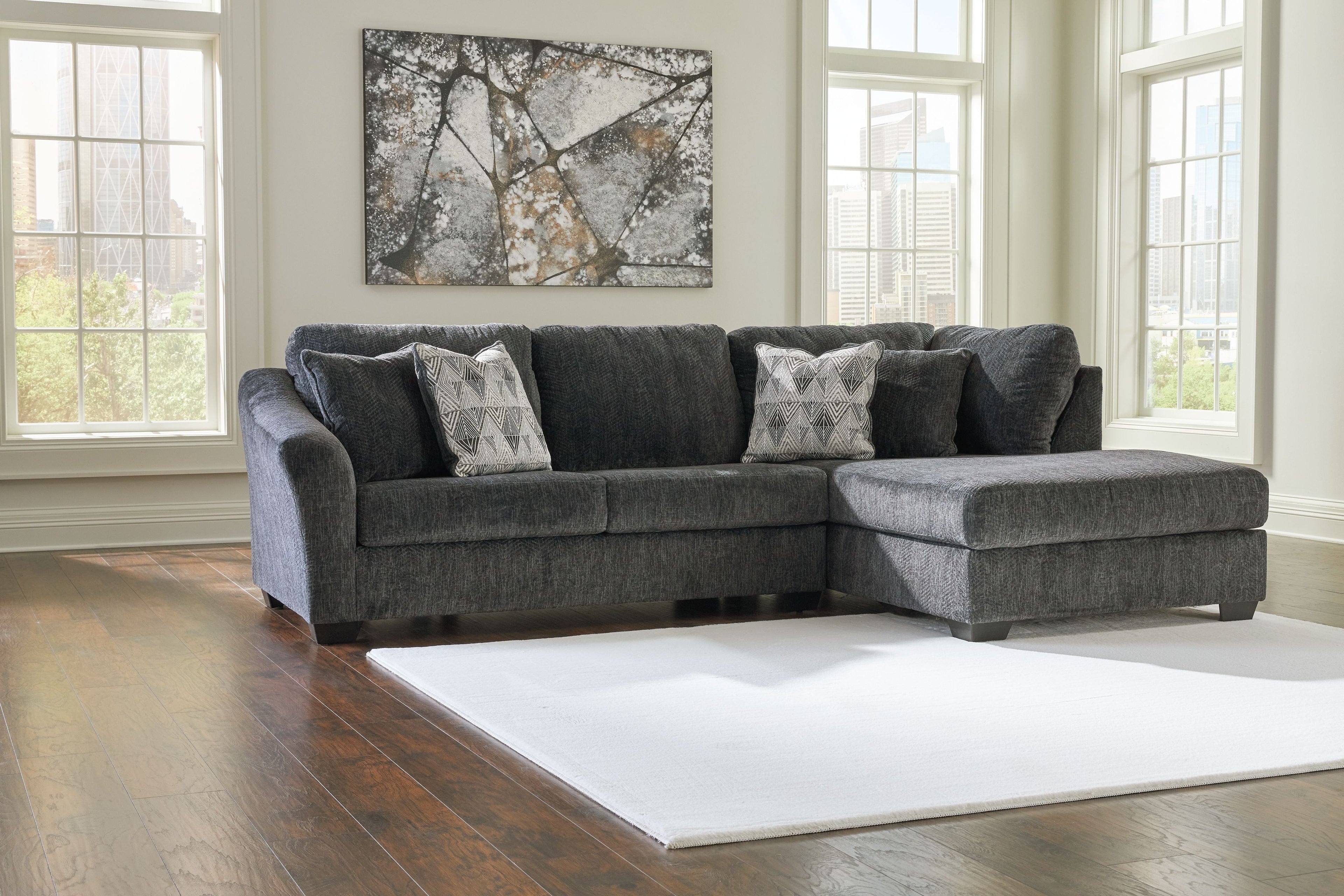 Dark gray sectional sofa with chaise corner and four accent pillows in light gray
