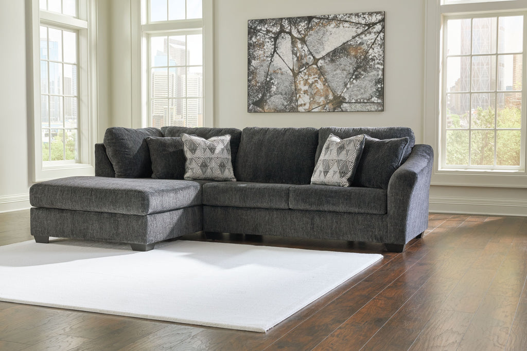 Dark gray corner sectional with chaise, tufted arms, and patterned accent pillows