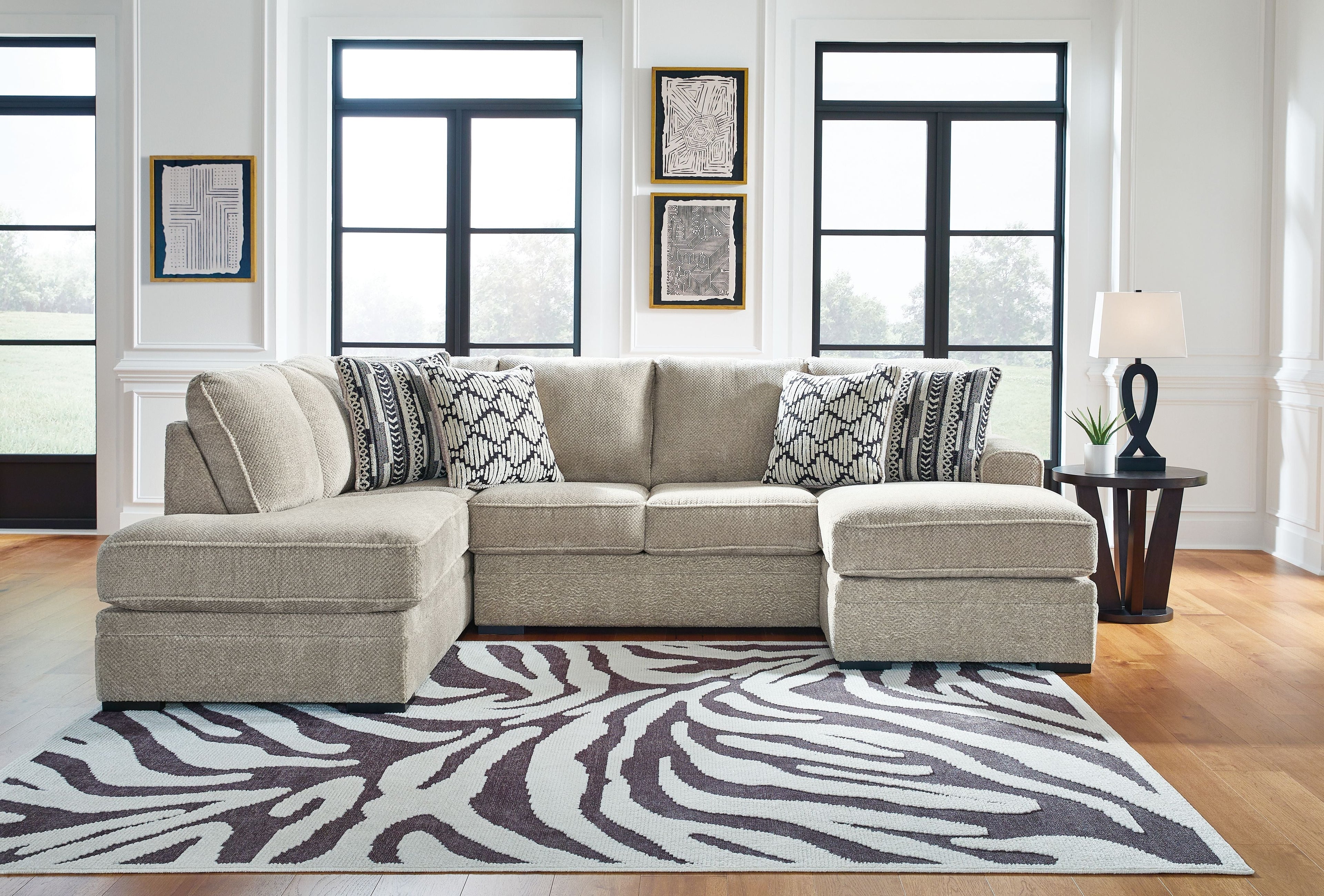 Light beige sectional sofa with chaise, tufted seat cushions, and patterned throw pillows