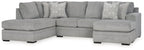Grey sectional sofa with corner chaise, armrests, and patterned throw pillows.