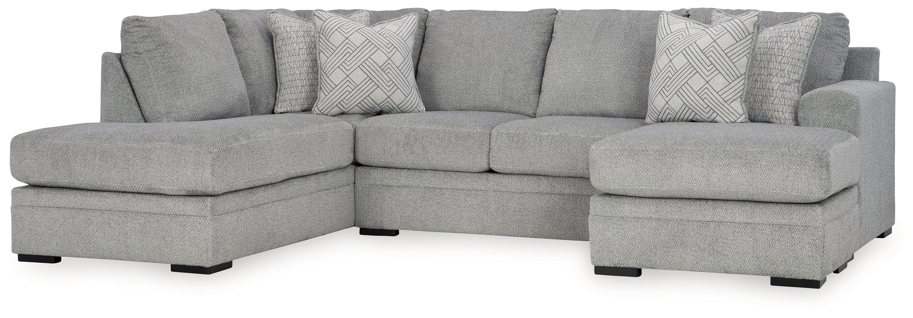 Grey sectional sofa with corner chaise, armrests, and patterned throw pillows.