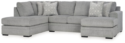 Grey sectional sofa with corner chaise, armrests, and patterned throw pillows.