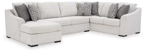 Stone sectional sofa with chaise and armrests, light upholstery, black feet, patterned accent pillows