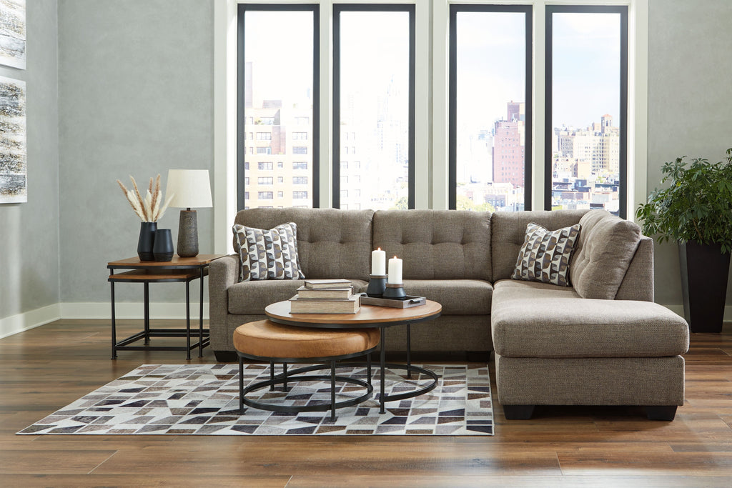 Gray sectional sofa with corner chaise and tufted back, patterned pillows and a matching ottoman