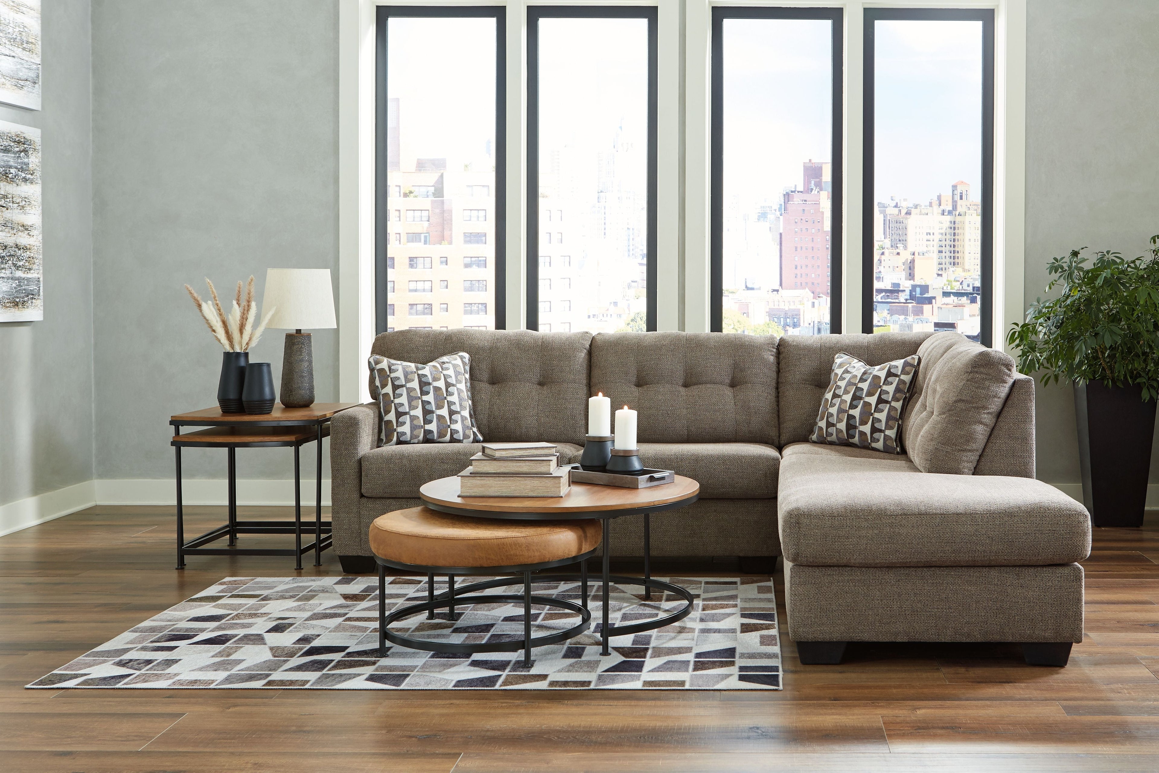 Gray sectional sofa with corner chaise and tufted back, patterned pillows and a matching ottoman