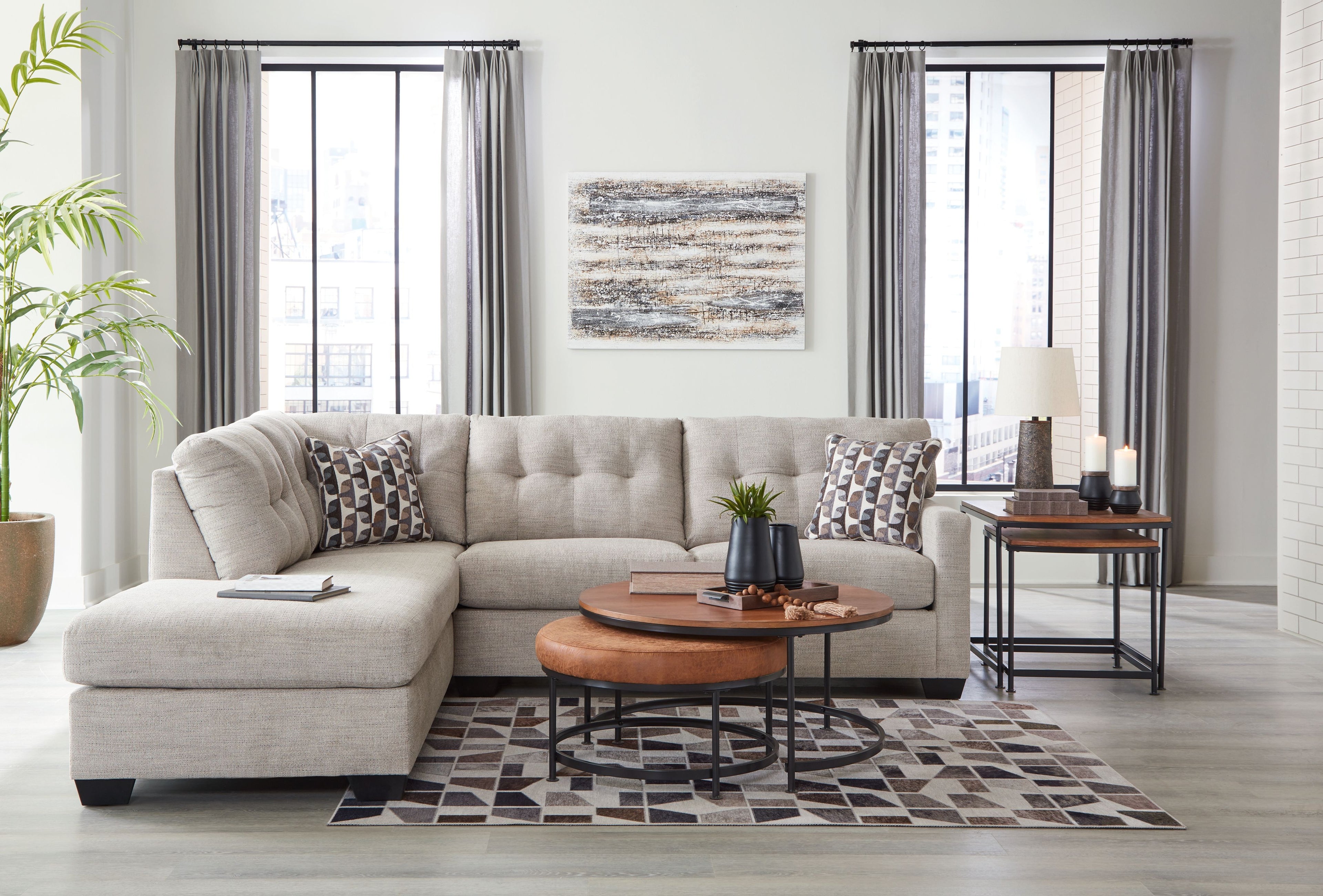 Light gray sectional sofa with chaise and patterned pillows, styled with throw blanket