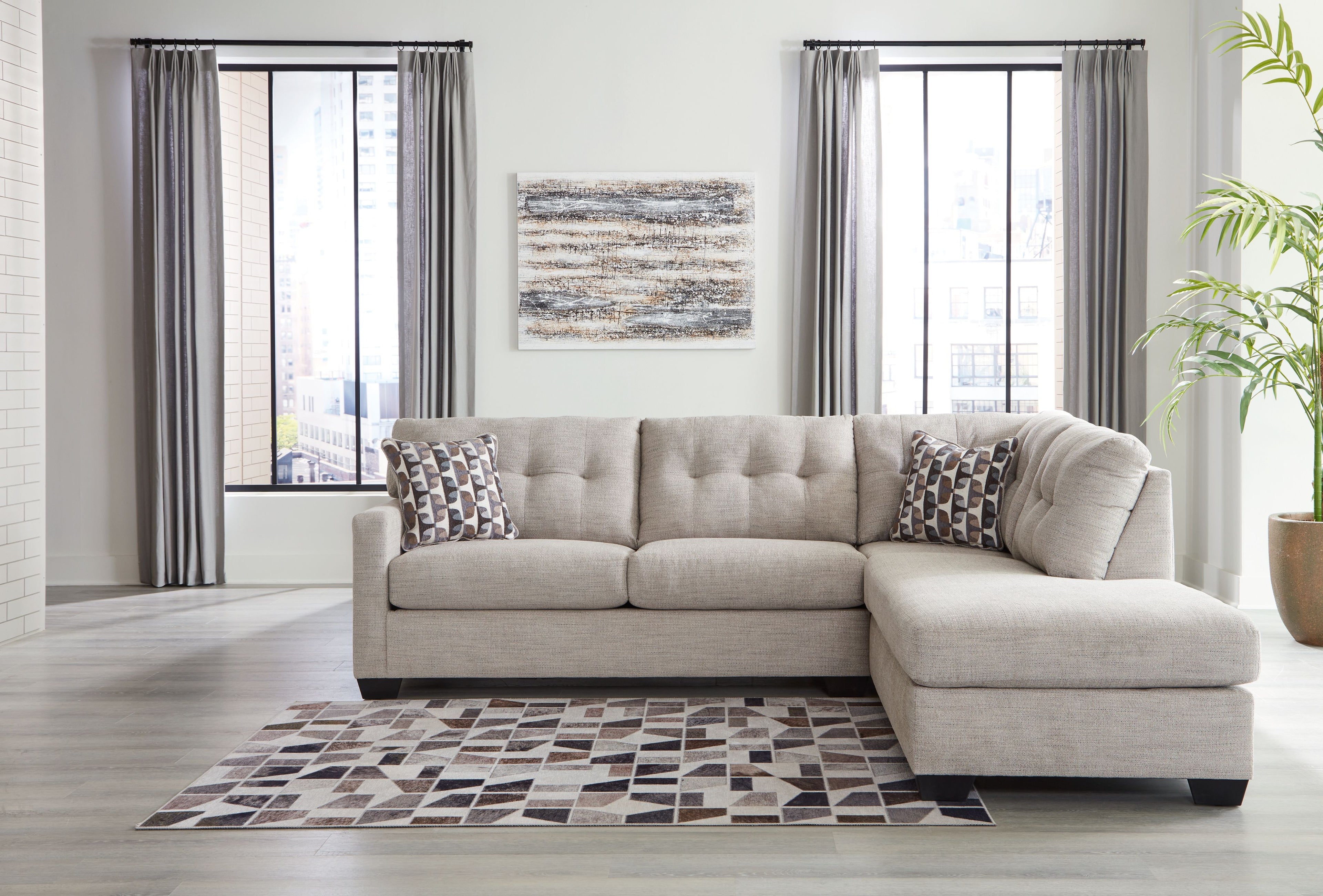 Light gray sectional with chaise and patterned pillows in a living room setting
