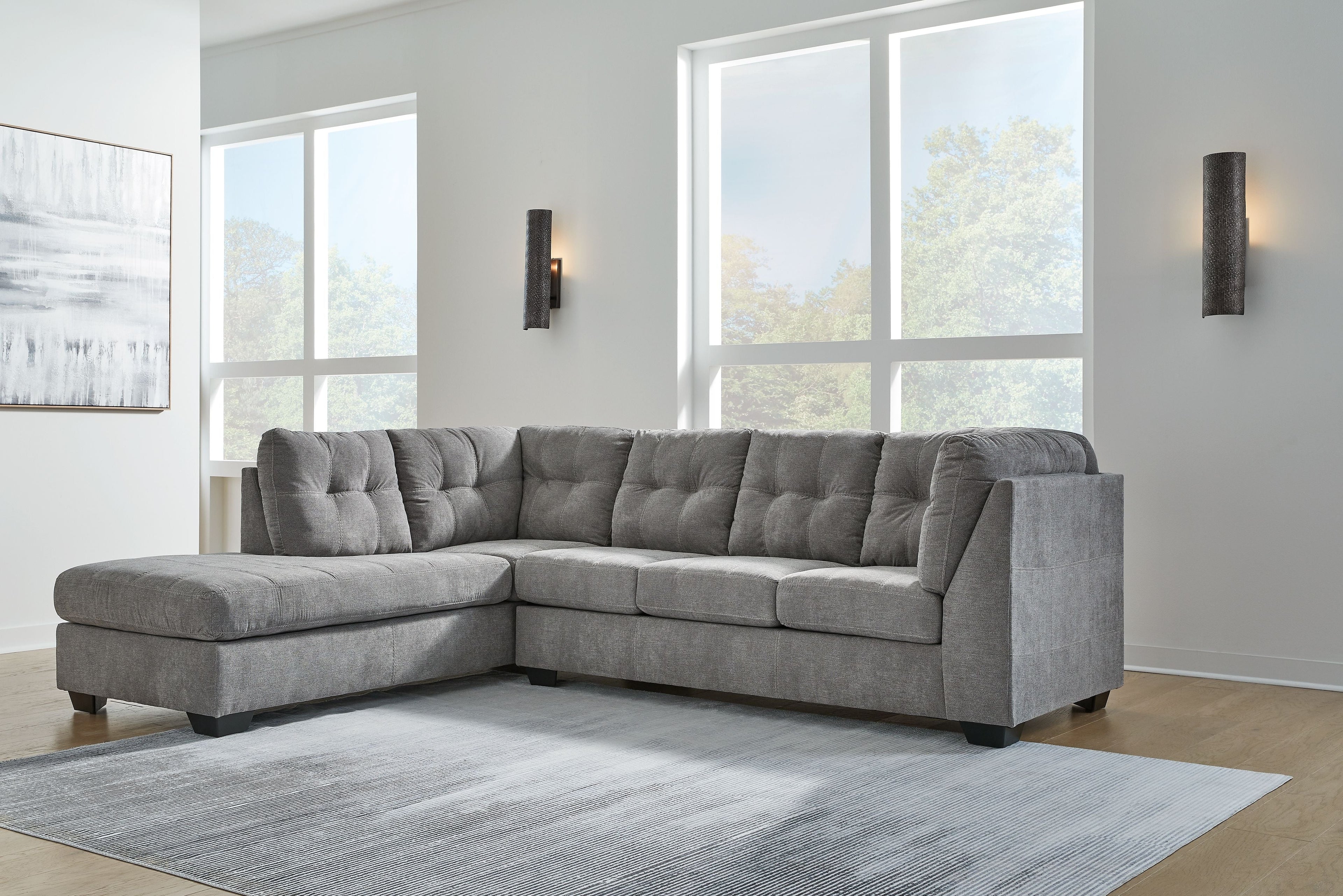 Gray sectional sofa with corner chaise, tufted back, and thick seat cushions in living room