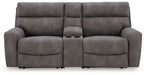 Power reclining sofa with three padded seats and chaise footrests, dark gray upholstery