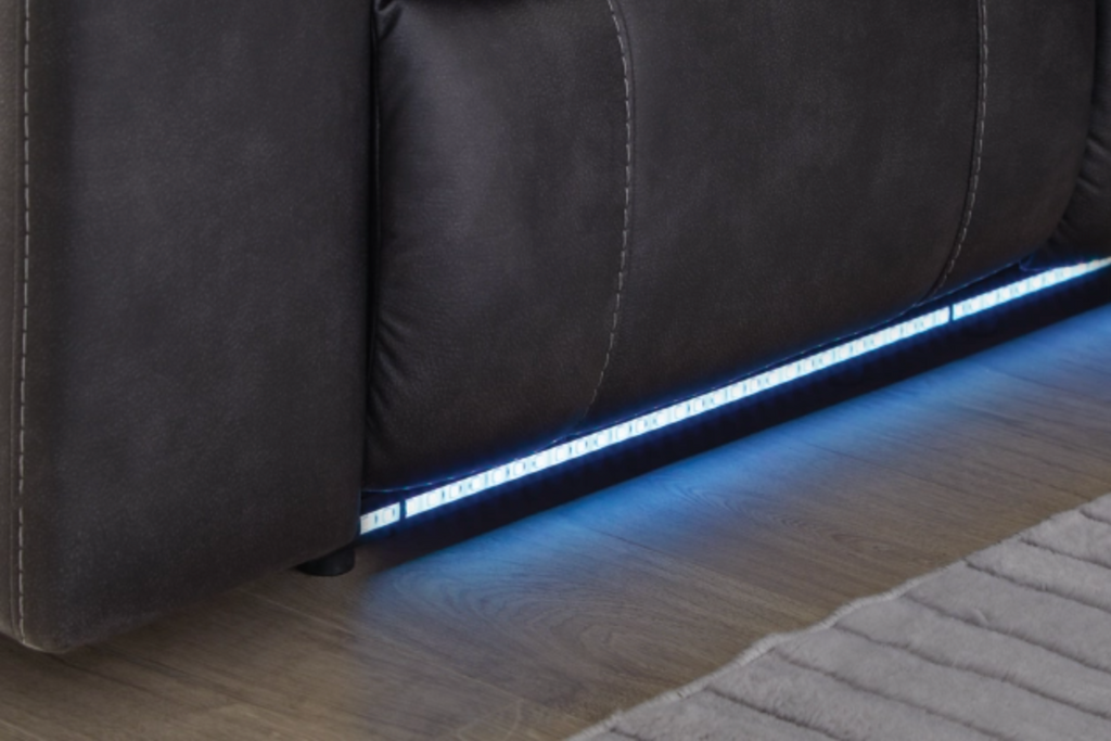 Dark carbon reclining sectional with glowing LED strip along the base and stitched cushions.