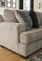 Stone fabric sectional sofa with rounded arms and patterned throw pillows