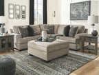Stone sectional sofa with corner chaise and patterned throw pillows, shown with ottoman