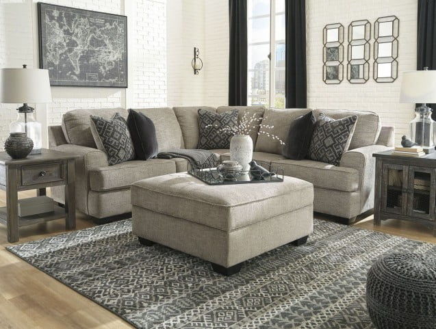 Stone sectional sofa with corner chaise and patterned pillows with small ottoman in front