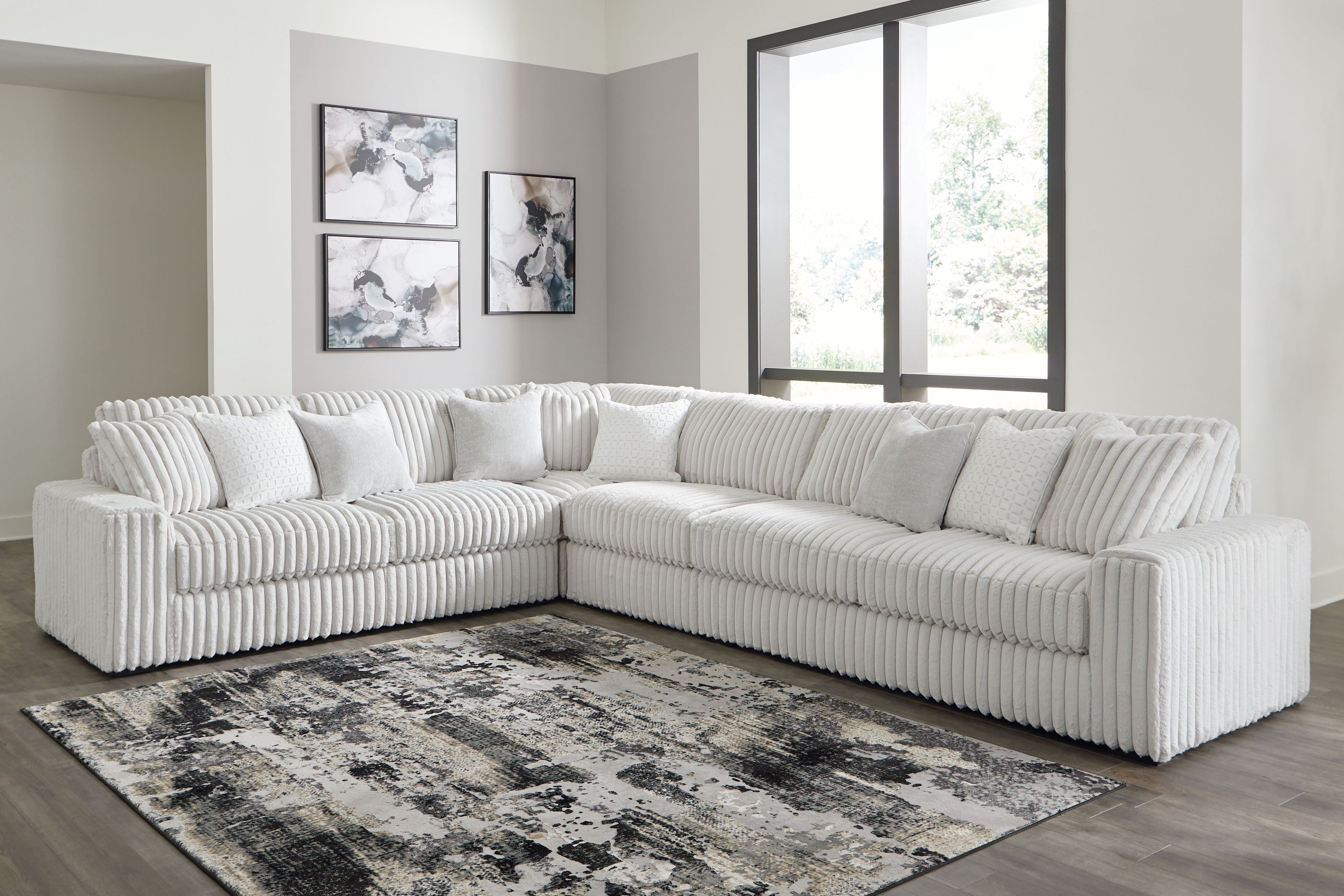 Light gray sectional sofa with multiple back pillows and ribbed chaise seating