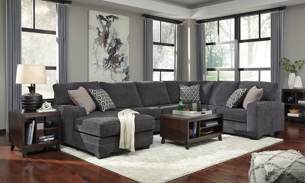 Dark gray sectional sofa with chaise, decorative pillows, and wide padded back cushions