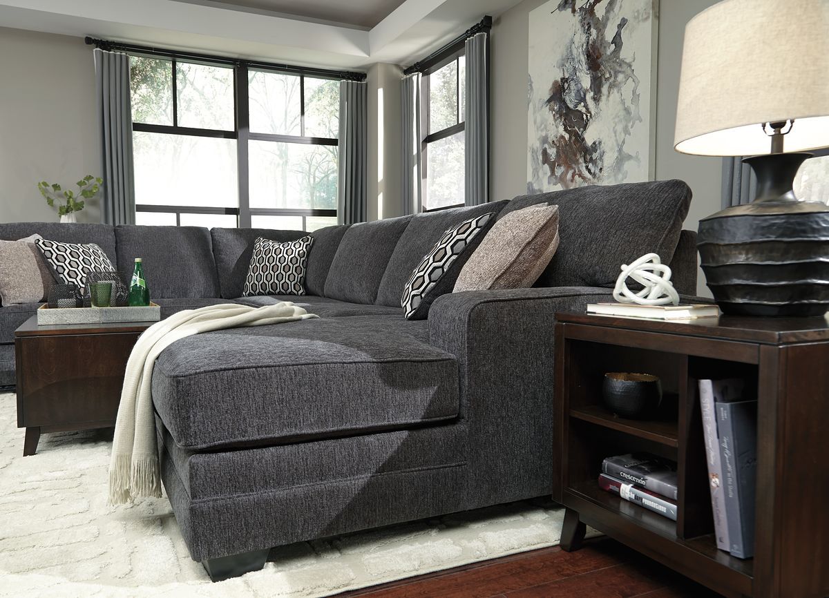 Dark gray sectional sofa with chaise and patterned throw pillows on a chaise end