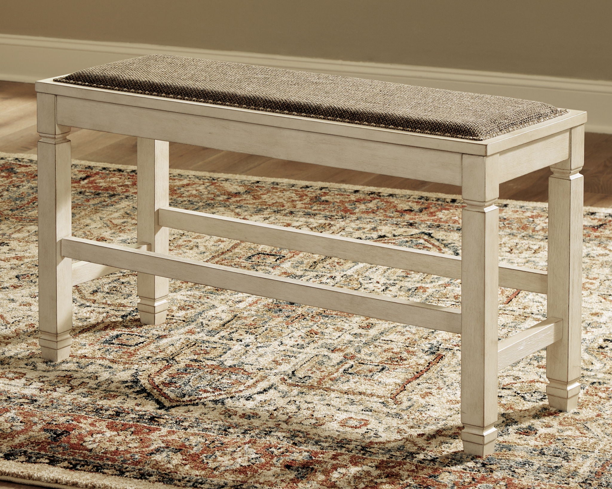Beige counter bench with upholstered seat and open lower shelf underframe